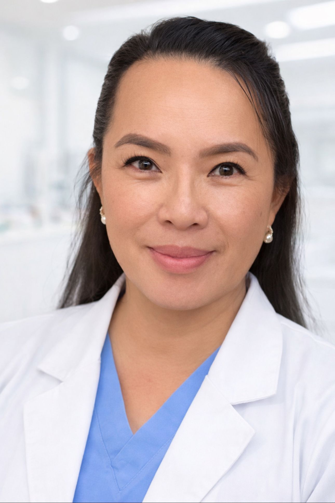 Mai Le, PA-C, CWS, WCC in a white lab coat and blue scrubs smiles warmly. The background is a softly blurred clinical setting, suggesting a medical environment.