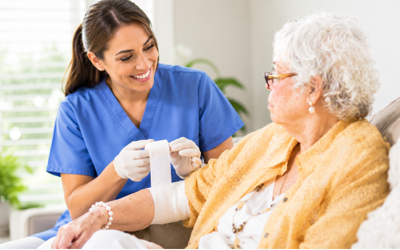 A wound care specialist treating an elderly patient comfortably at home